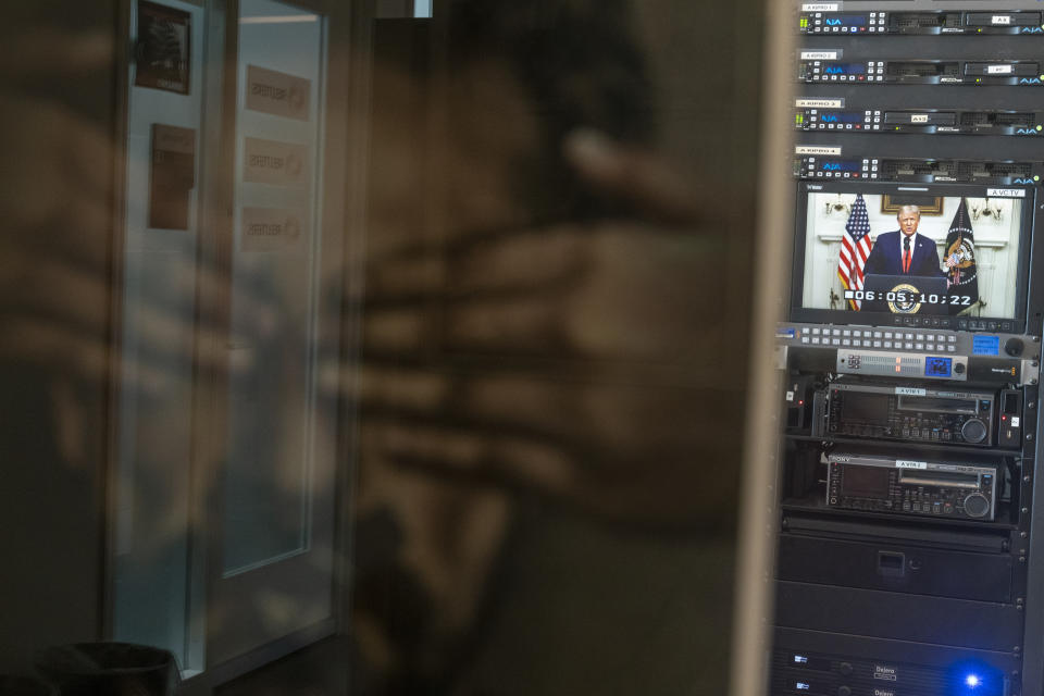 U.S. President Donald Trump is framed by a "Journalism is not a crime poster" as he is seen on a video screen in the Al Jazeera office remotely addressing the 75th session of the United Nations General Assembly, Tuesday, Sept. 22, 2020, at U.N. headquarters. This year's annual gathering of world leaders at U.N. headquarters will be almost entirely "virtual." Leaders have been asked to pre-record their speeches, which will be shown in the General Assembly chamber, where each of the 193 U.N. member nations are allowed to have one diplomat present. (AP Photo/Mary Altaffer)