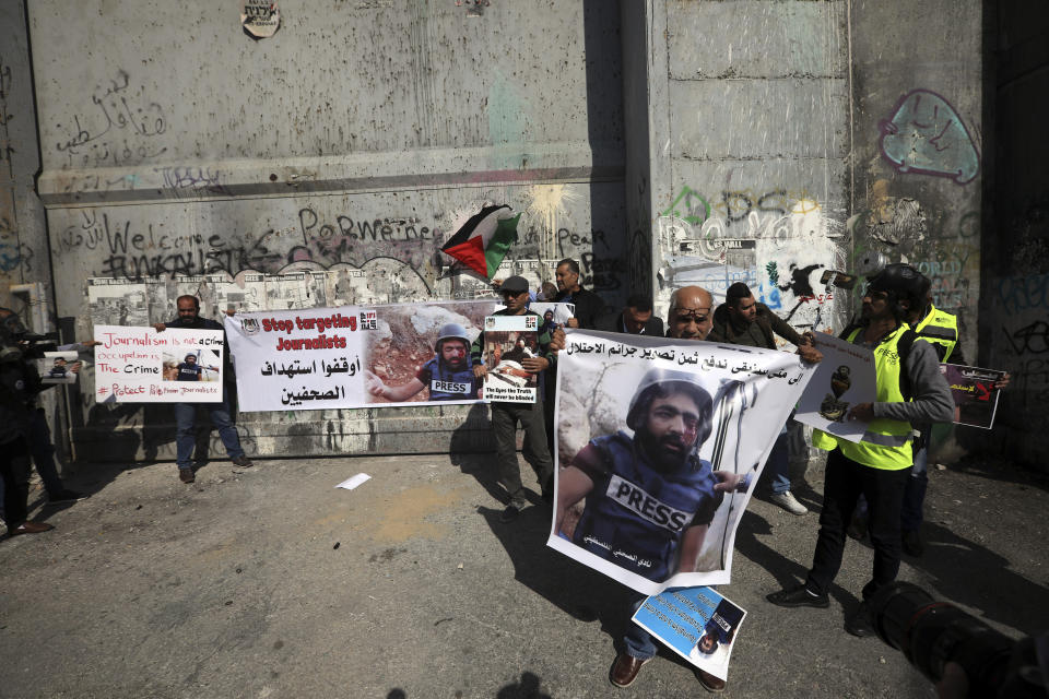 Palestinian journalist hold posters of a 35 year-old photographer Muath Amarneh in front of a separation barrier in Bethlehem, West Bank, Sunday, Nov. 18, 2019, during a protest in support . Amarneh's relatives say he has lost vision in one eye after apparently being struck by Israeli fire while covering a demonstration in the West Bank. Israel's paramilitary border police unit says it did not target him. (AP Photo/Mahmoud Illean)