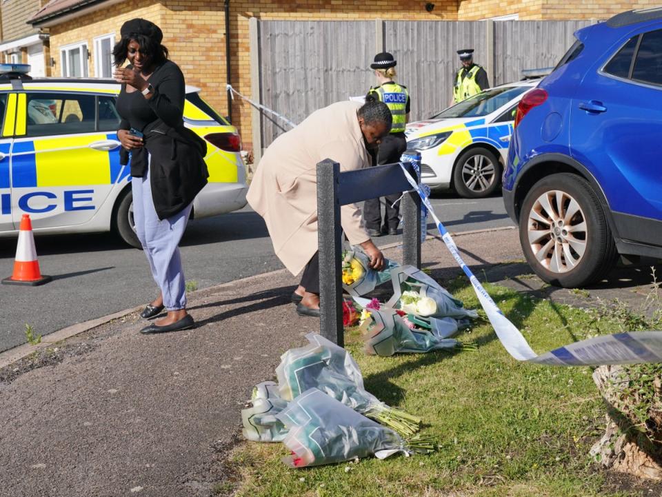 A woman delivers floral tributes near to the scene in Ashlyn Close, Bushey (Jonathan Brady/PA)