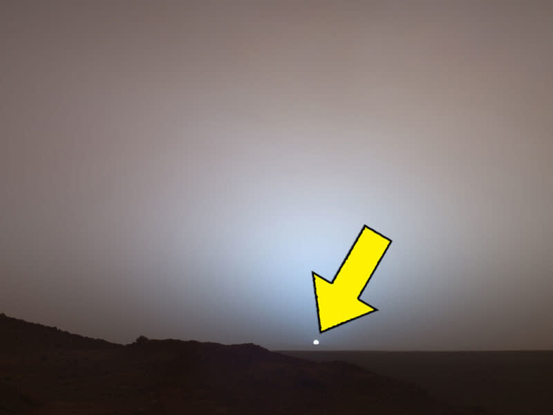 A small dot in the sky over Mars slinking behind a darkened landscape