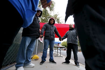 A prayer group holds hands as they pray outside the Inland Regional Center (IRC) as employees return to work for the first time following a shooting at the center, in San Bernardino, California January 4, 2016. REUTERS/Mike Blake