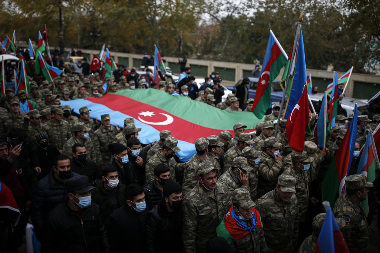 Azerbaijani soldiers carry a huge national flag as they celebrate the transfer of the Lachin region to Azerbaijan's control, as part of a peace deal that required Armenian forces to cede the Azerbaijani territories they held outside Nagorno-Karabakh, in Aghjabadi, Azerbaijan, Tuesday, Dec. 1, 2020. Azerbaijan has completed the return of territory ceded by Armenia under a Russia-brokered peace deal that ended six weeks of fierce fighting over Nagorno-Karabakh. Azerbaijani President Ilham Aliyev hailed the restoration of control over the Lachin region and other territories as a historic achievement. (AP Photo/Emrah Gurel)