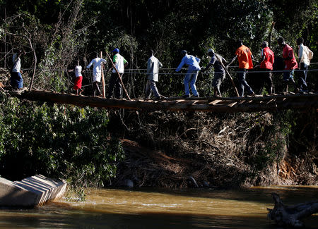 Survivors of cyclone Idai cross a temporary foot bridge to receive aid at Coppa business centre in Chipinge, Zimbabwe, March 25, 2019. Picture taken March 25, 2019. REUTERS/Philimon Bulawayo