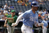 Oakland Athletics starting pitcher Jared Koenig throws to first for the out hit into by Kansas City Royals' Whit Merrifield, right, during the third inning of a baseball game Saturday, June 25, 2022, in Kansas City, Mo. (AP Photo/Charlie Riedel)