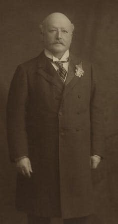 Full length photo of a balding man with glasses taken in the 1900s.