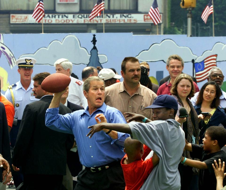 FILE - President George W. Bush celebrates the Fourth of July holiday in Philadelphia by playing street football with kids at a block party sponsored by the Greater Exodus Baptist Church to promote his faith-based initiative on July 4, 2001. (AP Photo/J. Scott Applewhite, File)