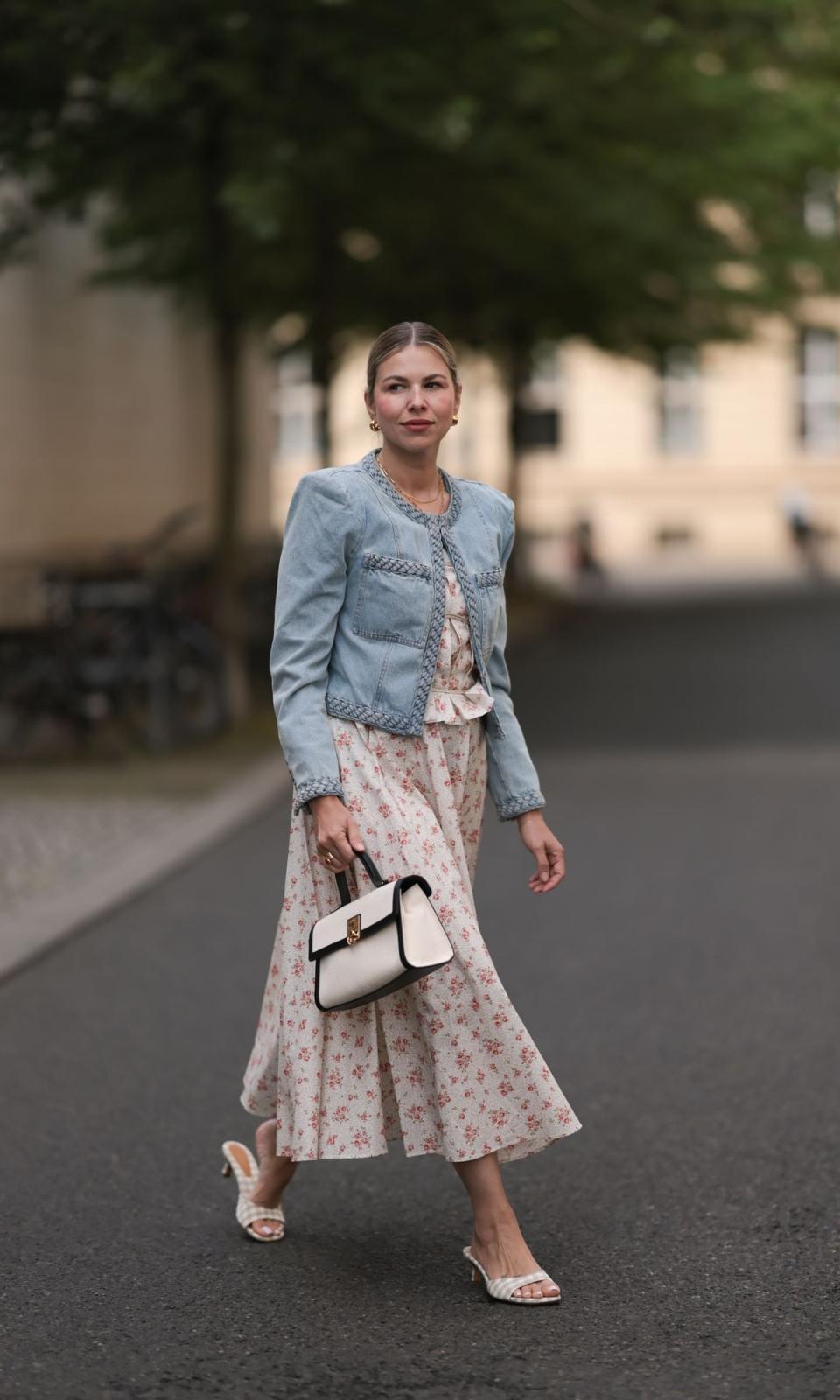 chaqueta vaquera ligera, vestido midi blanco crema con estampado floral rojo, un bolso blanco crema y mules a cuadros blancos y beige