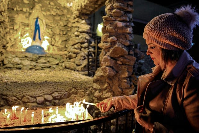 An Iraqi Christian woman lights candles during a Christmas Eve Mass in St Teresa’s Church ahead of Christmas celebrations, in Basra, Iraq (Nabil al-Jurani/AP)