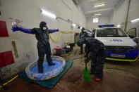 Volunteer workers of Search and Rescue (SAR) with special equipment, disinfect a volunteer after disinfecting a police car at Local Police station to prevent the spread of coronavirus COVID-19, in Pamplona, northern Spain, Sunday, March 22, 2020. For some people the COVID-19 coronavirus causes mild or moderate symptoms, but for some it causes severe illness. (AP Photo/Alvaro Barrientos)