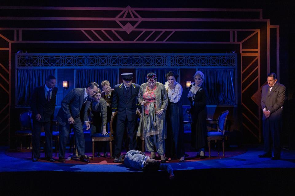 Passengers on the Orient Express stand, alarmed, over “Mary Debenham,” played by Jordan Boatman, who has accidentally shot herself with a revolver in the shoulder, in the Cape Playhouse production of Agatha Christie's "Murder on the Orient Express." The actors are, from left, Duane Boutte, Matt Bogart, Charlotte Bydwell, Ryan Meyer, Chris Tramantana, Cady Huffman, Emma Straton, Bianca Leigh, and Reg Rogers as detective Hercule Poirot.