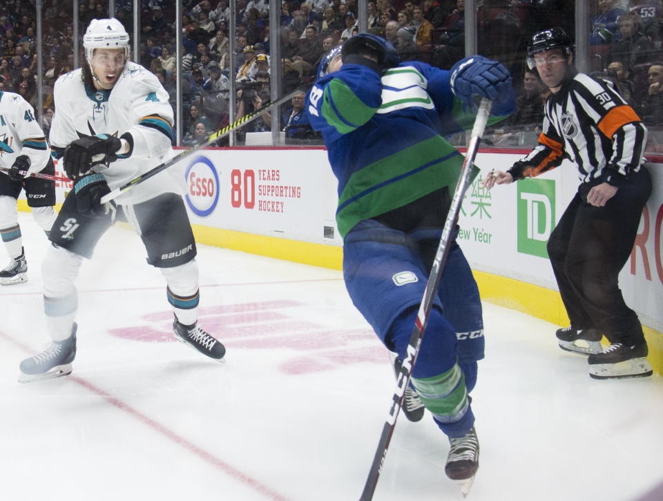 San Jose Sharks defenseman Brenden Dillon (4) high-sticks Vancouver Canucks right wing Jake Virtanen (18) during the second period of an NHL hockey game Saturday, Jan. 18, 2020, in Vancouver, British Columbia. (Jonathan Hayward/The Canadian Press via AP)