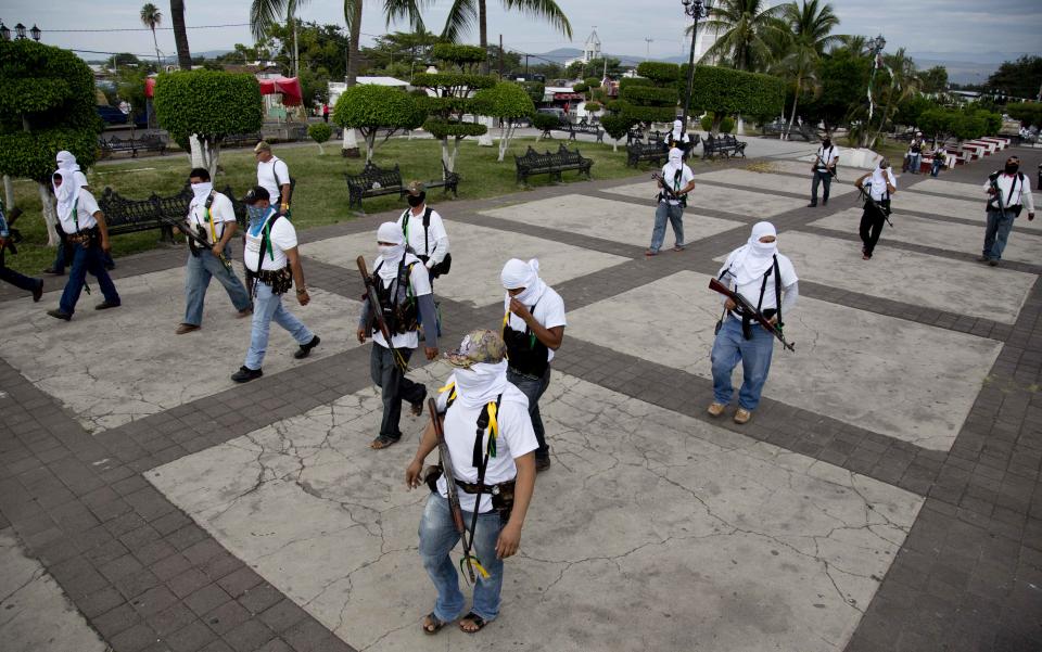 Men belonging to the Self-Defense Council of Michacan, (CAM), enter the main plaza the town of Nueva Italia, Mexico, Sunday Jan. 12, 2014. The vigilantes say they are liberating territory in the so-called Tierra Caliente and are aiming for the farming hub of Apatzingan, said to be the Knights Templar drug cartel's central command. Mexican military troops are staying outside the town and there are no federal police in sight. (AP Photo/Eduardo Verdugo)