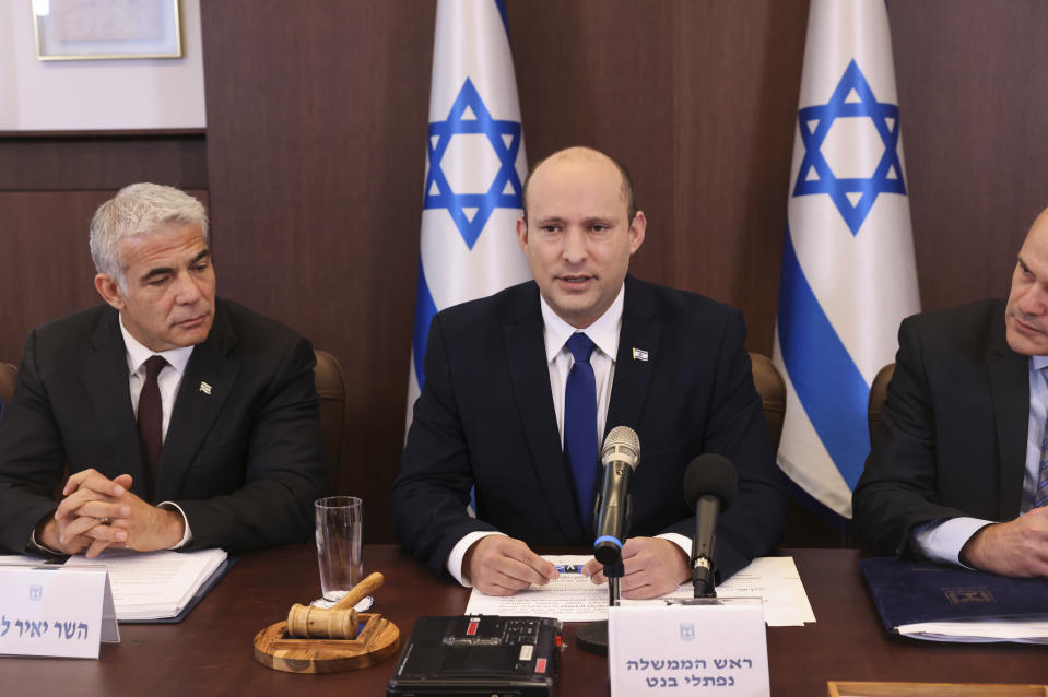 Israeli Prime Minister Naftali Bennett, center, flanked by Alternate Prime Minister and Foreign Minister Yair Lapid, left, chairs the first weekly cabinet meeting of the new government in Jerusalem, Sunday, June 20, 2021. Bennett opened his first Cabinet meeting on Sunday since swearing in his new coalition government with a condemnation of the newly elected Iranian president, whom he called “the hangman of Tehran.” (Emmanuel Dunand/Pool Photo via AP)