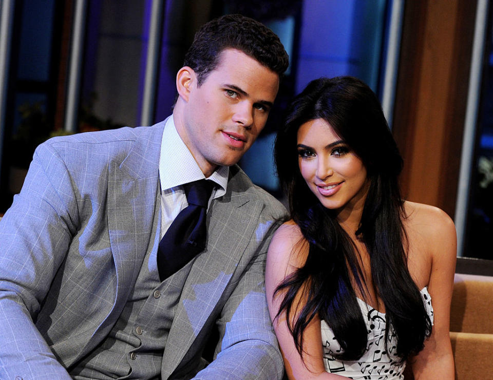 Kris Humphries in a suit and tie, and Kim Kardashian in a strapless patterned dress, sitting closely and smiling at an event