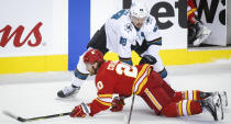 San Jose Sharks' Tomas Hertl, right, takes down Calgary Flames' Blake Coleman during the first period of an NHL hockey game, Tuesday, Nov. 9, 2021 in Calgary, Alberta. (Jeff McIntosh/The Canadian Press via AP)