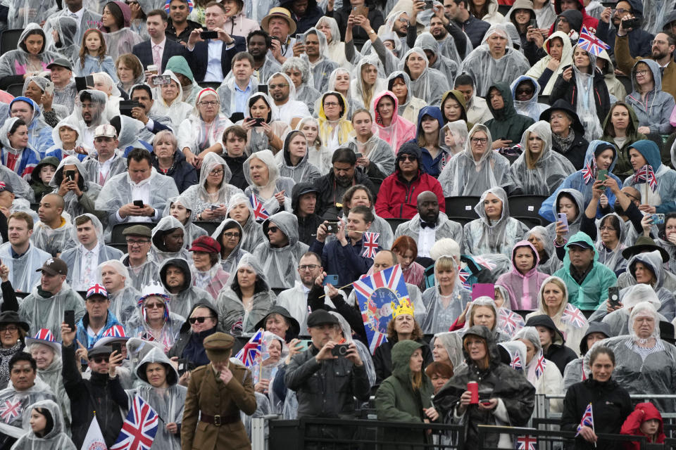 Gente bajo la lluvia en tribunas junto al Palacio de Buckingham antes de la ceremonia de coronación del rey Carlos III de Gran Bretaña en Londres, el sábado 6 de mayo de 2023. (Foto AP/Frank Augstein)