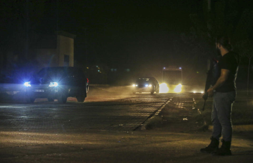 In this late Friday, Oct. 18, 2019 photo, Turkish police and army cars escort vans and buses returning from Syria, reportedly carrying IS group members and their families, at the border town of Akcakale, Sanliurfa province, southeastern Turkey. Turkey's interior minister Suleyman Soylu said Saturday, Oct. 19, that 41 Islamic State members were re-captured in Syria and private IHA news agency said the Turkish nationals among the re-captured were brought over to Turkey in vans. Turkey's President Recep Tayyip Erdogan Erdogan said the Turks captured would be imprisoned and tried in Turkey. (AP Photo/Emrah Gurel)