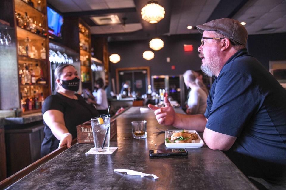 Jay Estes talks to employee Frances Lavoie at Patio 44's bar as many restaurants resume dine-in services in Hattiesburg, Miss., Monday, May 18, 2020.