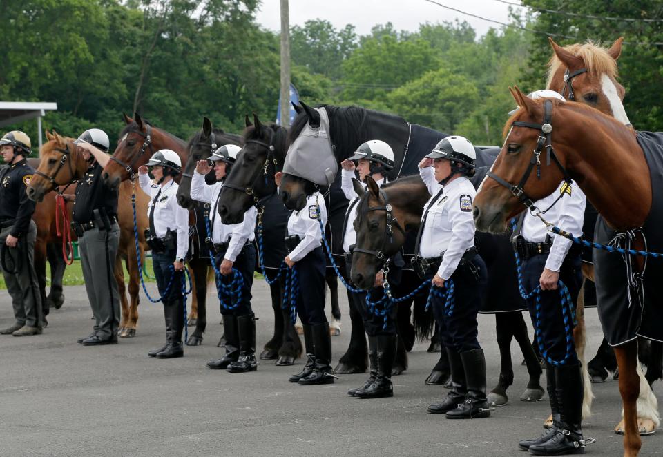 Members of the Columbus Division of Police's mounted unit stand and salute during a memorial event for Liberty, a 16-year-old Belgian horse in June.