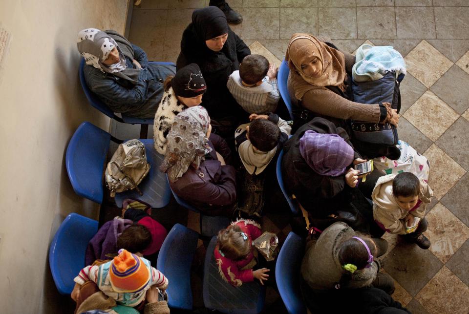 FILE - In this Wednesday, Dec. 18, 2013, file photo, Syrian women wait with their children at the U.N. refugee agency's registration center in Zahleh, in Lebanon's Bekaa Valley. An international charity organization Save Children has warned Monday, March 10, 2014 of a health care disaster in Syria with newborns dying in hospital incubators during power cuts and children having their limbs amputated for lack of alternative treatment. (AP Photo/Maya Alleruzzo, File)