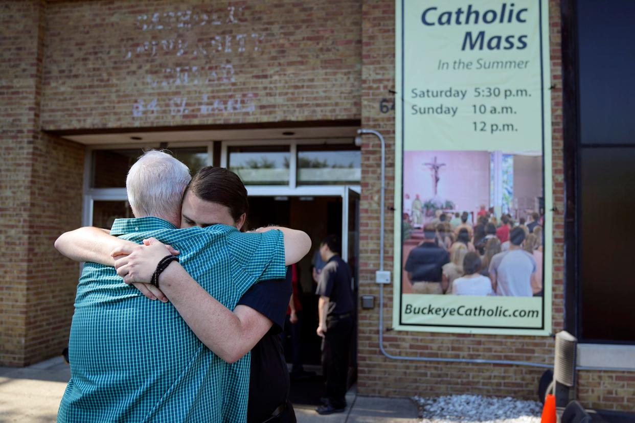 Jul 3, 2022; Columbus, Ohio, USA;  Fr. Evan Cummings hugs Greg Stype as he and other parishioners walk into the Newman Center, the parish and student ministry at Ohio State, for Catholic mass on July 3, 2022. Parishioners learned this week that the diocese is being taken from the Paulist fathers, an order of Catholic priests, who have run it for 65 years.  Mandatory Credit: Adam Cairns-The Columbus Dispatch