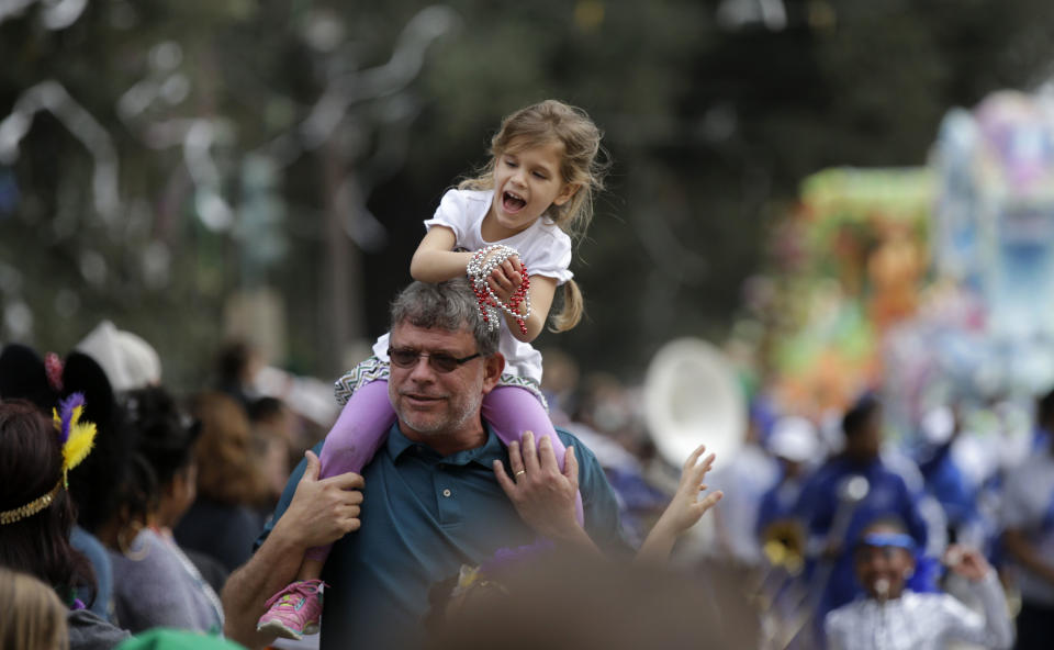 A child reacts after catching beads being thrown from a float during the Krewe of Proteus Mardi Gras parade in New Orleans, Monday, Feb. 16, 2015. 