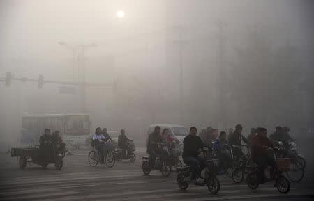 Residents ride bicycles along a street amid heavy haze in Xingtai, Hebei province November 3, 2013. REUTERS/China Daily