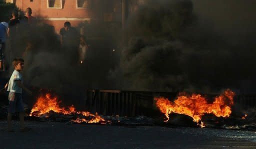 A Lebanese boy walks past burning tyres which Sunni Muslim residents of the town of al-Abdeh ignited to block the highway leading to the northern Lebanese area of Akka. Street battles between pro- and anti-Syrian groups in Beirut killed two people on Monday, a security official said, sparking concerns of a wider conflict in Lebanon