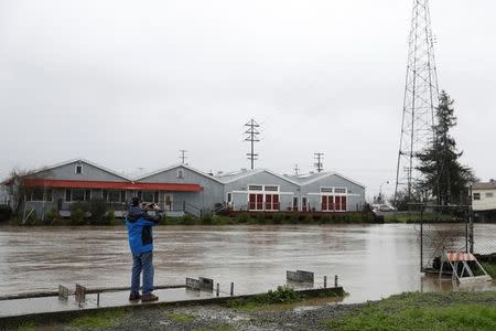 A man takes a photograph of a rising Petaluma River during a winter storm in Petaluma, California, January 8, 2017. REUTERS/Stephen Lam