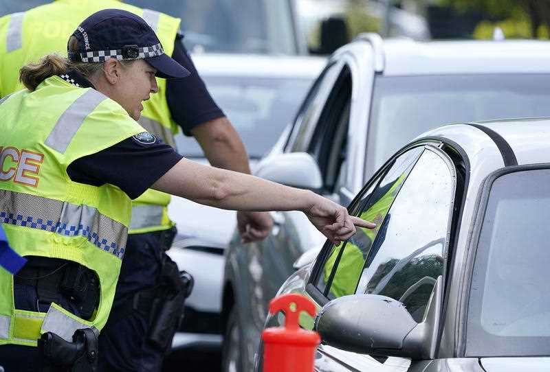 A police officer gestures to a driver at a checkpoint at Coolangatta on the Queensland-New South Wales border.