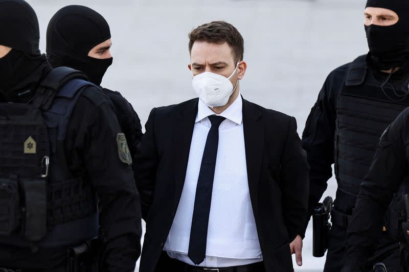 FILE PHOTO: A 33-year-old man, who is charged with the intentional homicide of his 20-year-old wife, is escorted to the court for the beginning of his trial, in Athens