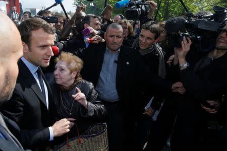 Emmanuel Macron (L), head of the political movement En Marche !, or Onwards !, and candidate for the 2017 French presidential election, is surrounded by journalists as he arrives to talk to Whirlpool employees in front of the company plant in Amiens, France, April 26, 2017. REUTERS/Pascal Rossignol