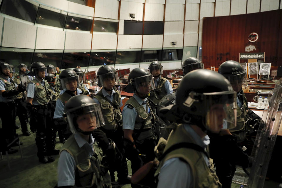 Police officers with protective gear retake the meeting hall of the Legislative Council in Hong Kong, during the early hours of Tuesday, July 2, 2019. Hundreds of protesters in Hong Kong swarmed into the legislature's main building Monday night, tearing down portraits of legislative leaders and spray-painting pro-democracy slogans on the walls of the main chamber as frustration over a lack of response from the administration to opposition demands boiled over. (AP Photo/Kin Cheung)