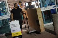 Employee at Best Buy electronics store helps to move out a television after a shopper made a purchase during Black Friday deals in Westbury
