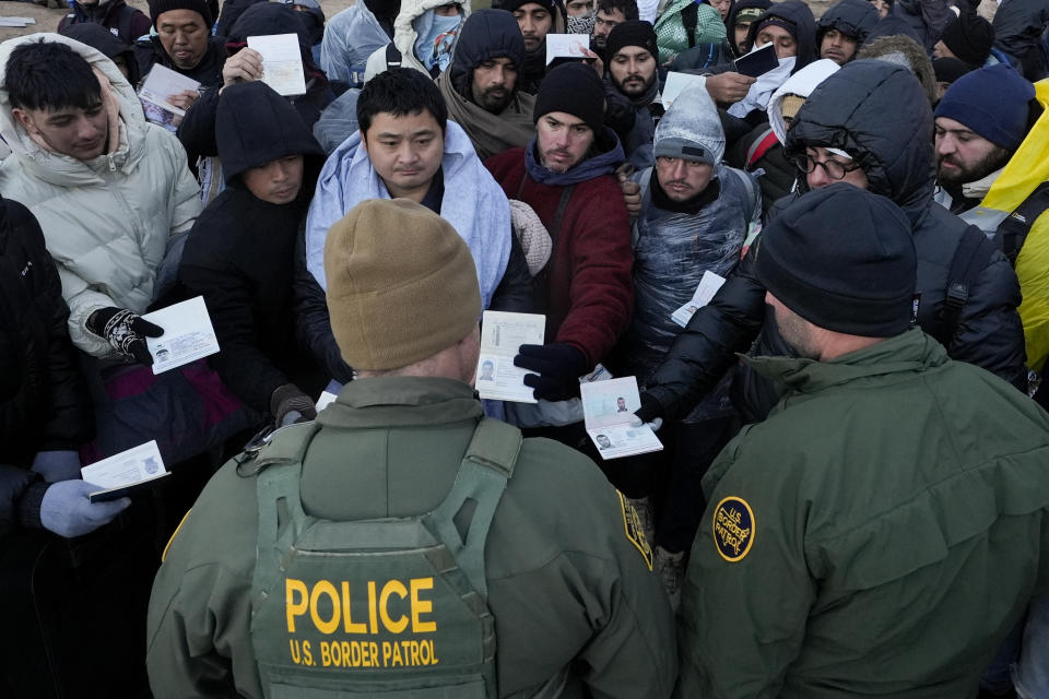 Border Patrol agents ask asylum-seeking migrants to line up in a makeshift, mountainous campsite after the group crossed the border with Mexico, Friday, Feb. 2, 2024, near Jacumba Hot Springs, Calif. (AP Photo/Gregory Bull)