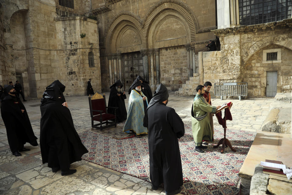 Arminian orthodox priests hold a mass outside closed Church of the Holy Sepulchre, where Christians believe Jesus Christ was buried, in Jerusalem, Saturday, March 28, 2020, as Israel tightens measures to fight the spread of the coronavirus. (AP Photo/Mahmoud Illean)