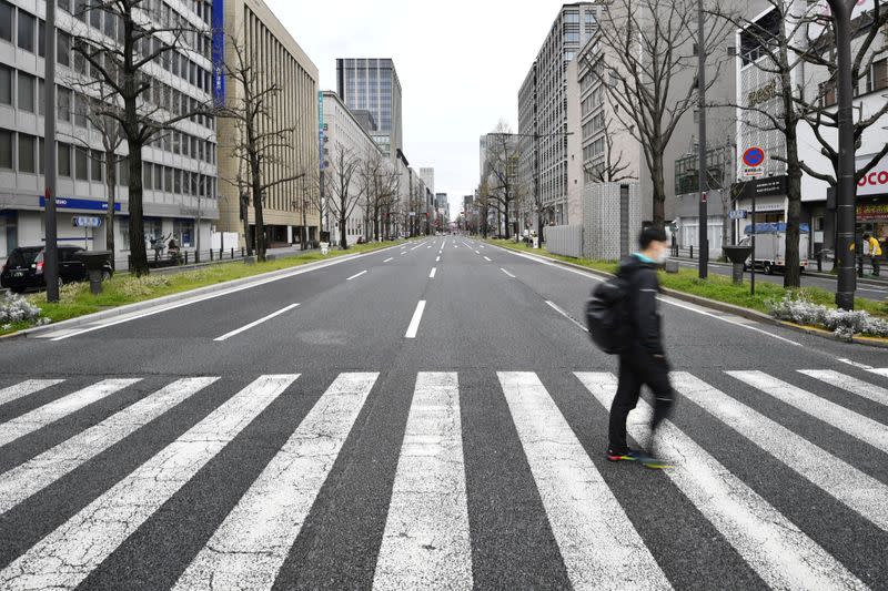 A man wearing a protective face mask, following an outbreak of the coronavirus disease, walks on a nearly empty street in Osaka