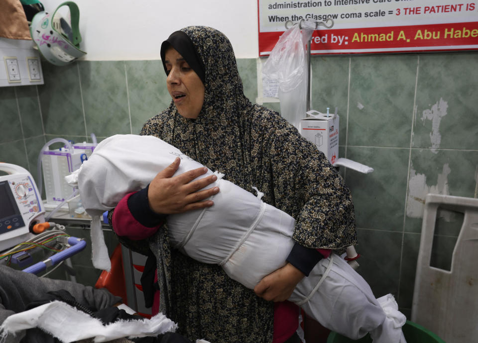 Suzan Zourob, the grandmother of two Palestinian children, new-born Al-Amera Ayesha and a young boy Ahmed Zourob, who were both killed in an Israeli strike amid the ongoing conflict between Israel and the Palestinian group Hamas, holds a child's body next to the baby's wounded parents, in Rafah, in the southern Gaza Strip, Dec. 19, 2023. / Credit: IBRAHEEM ABU MUSTAFA /REUTERS