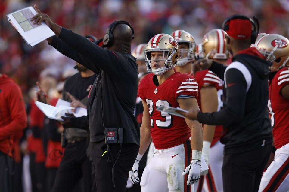 San Francisco 49ers running back Christian McCaffrey stands near assistant coach Anthony Lynn, left.