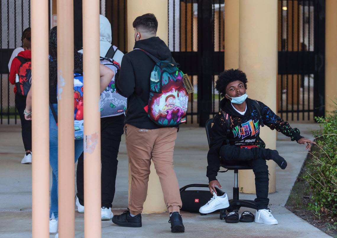 Music plays from a speaker as buses and parents drop off students for the first day at Miami Carol Senior High School, 3301 Miami Gardens Dr., in Miami Gardens on Wednesday morning. One student changes his shoes upon arrival.