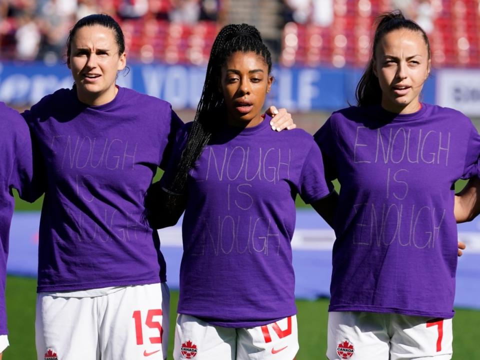 Canada's Evelyne Viens, left, Ashley Lawrence, centre and Julia Grosso are seen wearing 'Enough is enough' shirts in a team protest during the national anthem. (LM Otero/The Associated Press - image credit)