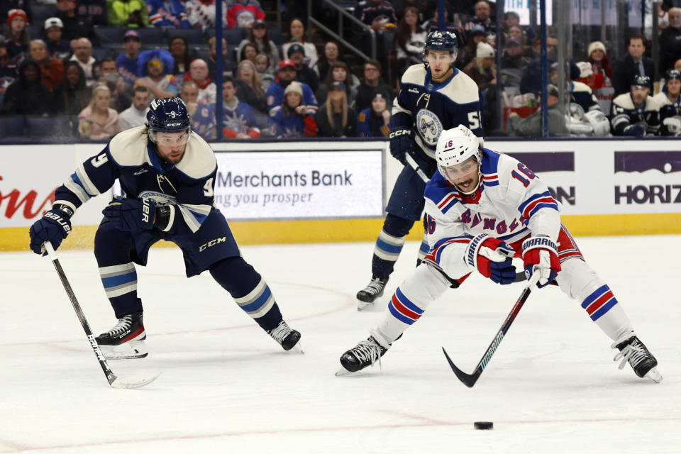 New York Rangers forward Vincent Trocheck, right, reaches for the puck in front of Columbus Blue Jackets defenseman Ivan Provorov, left, and forward Yegor Chinakhov, back right, during the first period of an NHL hockey game in Columbus, Ohio, Sunday, Feb. 25, 2024. (AP Photo/Paul Vernon)