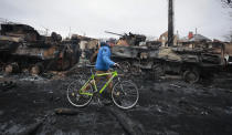 A man walks past the remains of Russian military vehicles in Bucha, close to the capital Kyiv, Ukraine, Tuesday, March 1, 2022. Russia on Tuesday stepped up shelling of Kharkiv, Ukraine's second-largest city, pounding civilian targets there. Casualties mounted and reports emerged that more than 70 Ukrainian soldiers were killed after Russian artillery recently hit a military base in Okhtyrka, a city between Kharkiv and Kyiv, the capital. (AP Photo/Serhii Nuzhnenko)