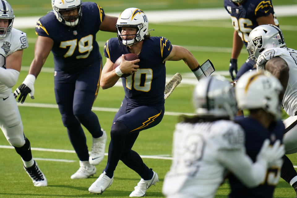 Los Angeles Chargers quarterback Justin Herbert, center, runs with the ball during the first half of an NFL football game against the Las Vegas Raiders, Sunday, Nov. 8, 2020, in Inglewood, Calif. (AP Photo/Alex Gallardo)