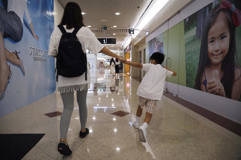 Pamela Lam plays with her son on the way to school in Hong Kong, Friday, July 3, 2020. Lam's 6-year-old son fell in love with the Hong Kong protest anthem, "Glory to Hong Kong," the first time he heard it and sings it quite often. Thanks to a sweeping new national security law, though, singing it in public is now risky. Lam agreed to be photographed only if her face was not shown, fearing possible retribution from authorities. (AP Photo/Kin Cheung)