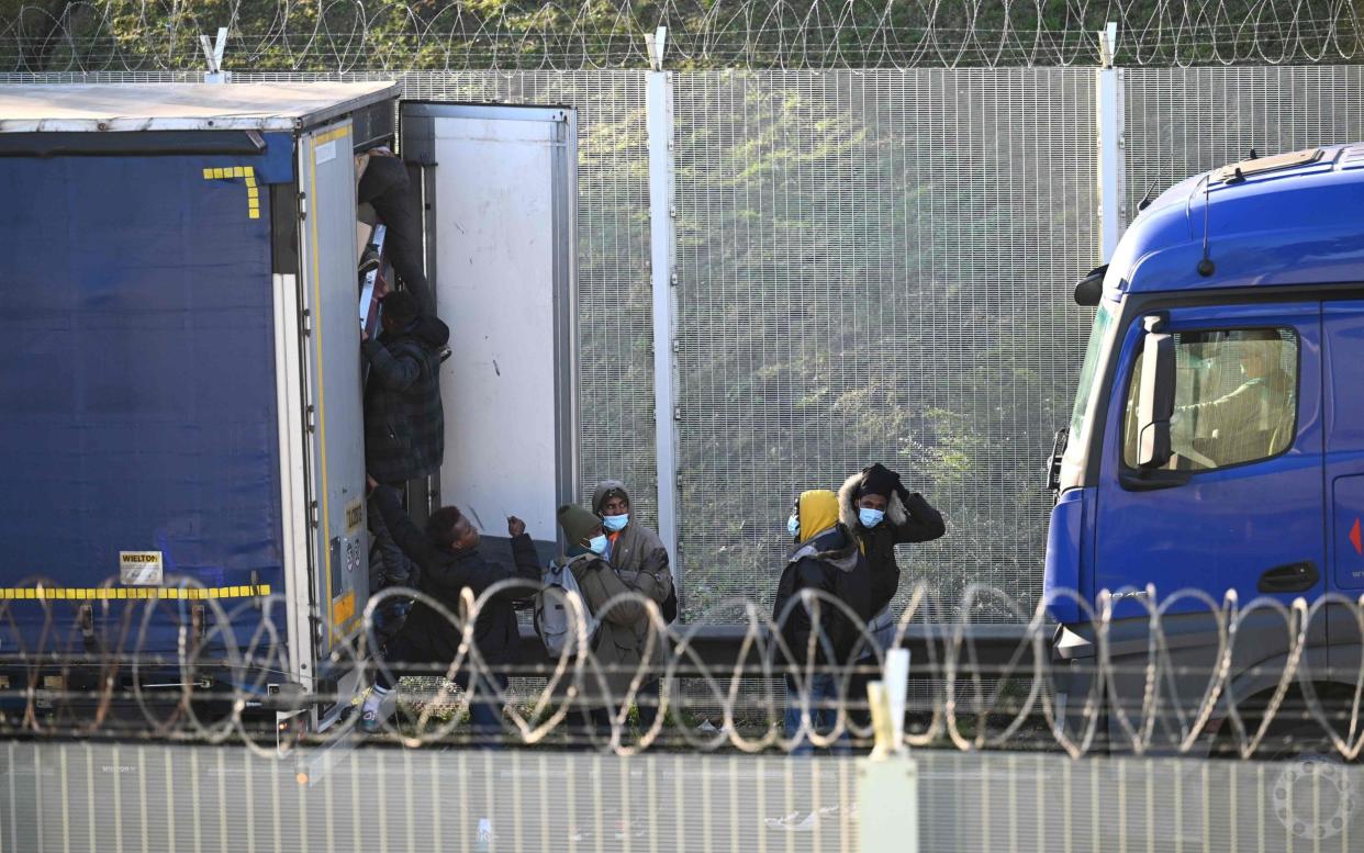 A man climbs into the back of a lorry bound for Britain while traffic is stopped waiting to board shuttles at the entrance to the Channel Tunnel in Calais in early December - Denis Charlet/AFP
