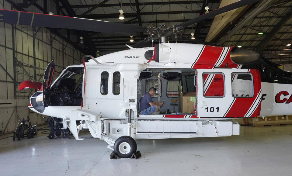 Avionics mechanic Mike Luong works on a Sikorsky Firehawk helicopter at the California Department of Forestry and Fire Protection's Sacramento Aviation Management Unit based at McClellan Airpark in Sacramento, Calif., Friday, July 23, 2021. Firefighters are trying to become smarter in how they prepare for the drought- and wind-driven wildfires that have become more dangerous across the American West in recent years, including by adding aircraft like the Sikorsky Firehawk helicopters or military surplus C-130 transport aircraft retrofitted to drop fire retardant. (AP Photo/Rich Pedroncelli)