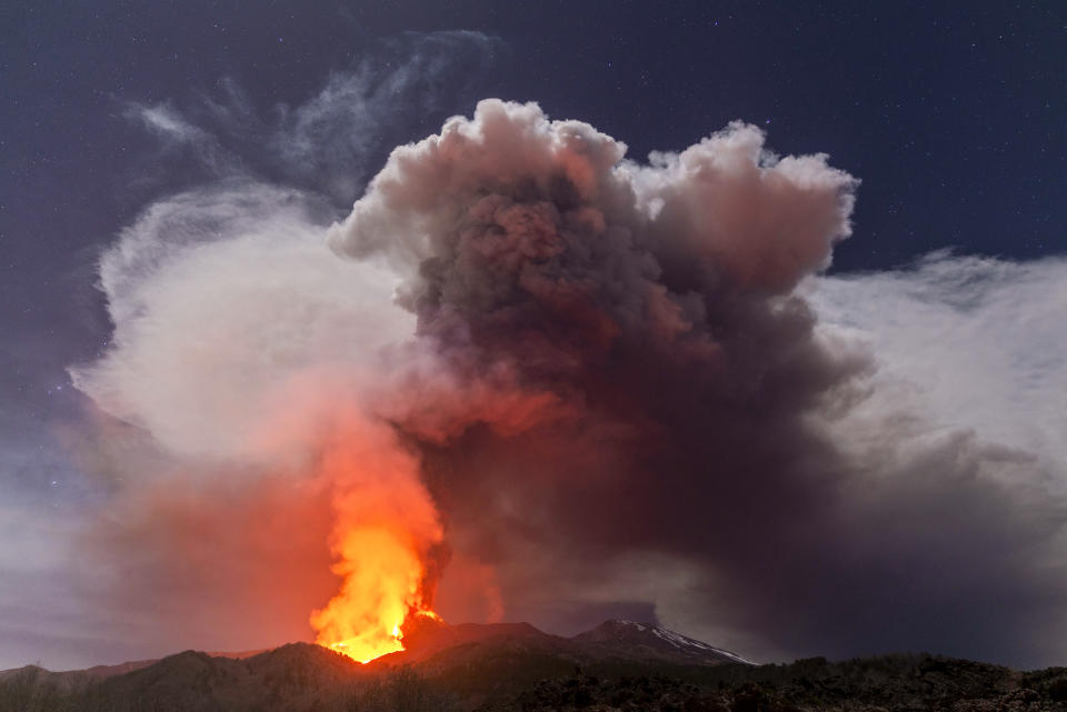 Glowing lava is seen from the north-east side of the Mt Etna volcano engulfed with ashes and smoke near Milo, Sicily, Wednesday night, Feb. 24, 2021. Europe's most active volcano has been steadily erupting since last week, belching smoke, ash, and fountains of red-hot lava. (AP Photo/Salvatore Allegra)