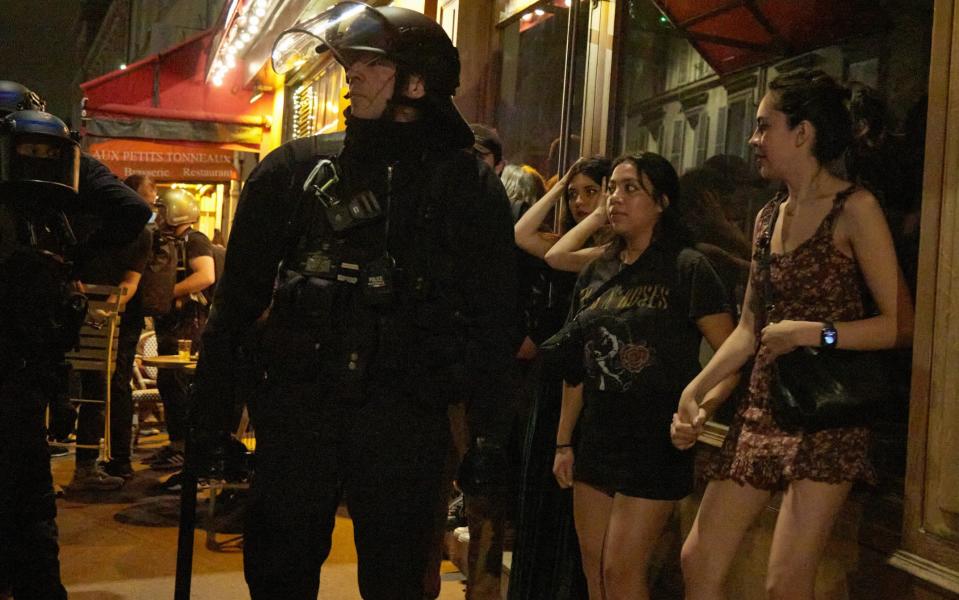 Police and passers-by look on as protests erupt in Paris