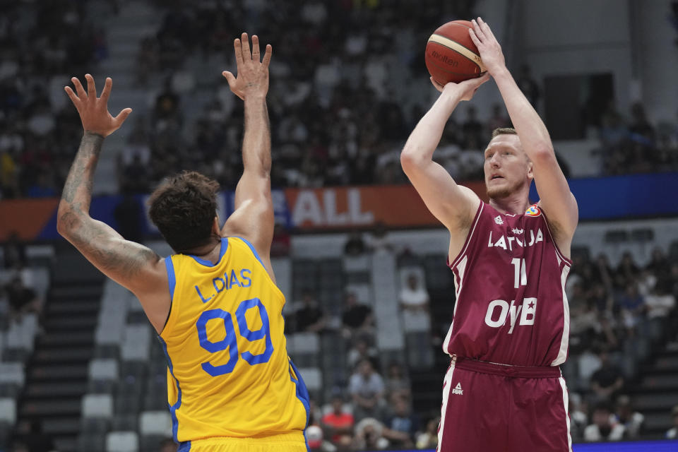 El alero de Letonia Rolands Smits lanza el balón sobre el alero de Brasil Lucas Dias en el encuentro de segunda ronda de la Copa Mundial de baloncesto en Jakarta el domingo 3 de septiembre del 2023. (AP Foto/Tatan Syuflana)